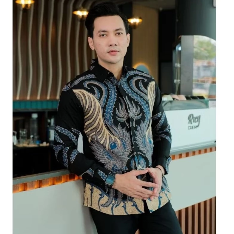 Front view close-up of a man in a black long-sleeve batik shirt with gold and blue phoenix patterns, clasping his hands and wearing a smartwatch, ideal for business casual occasions.